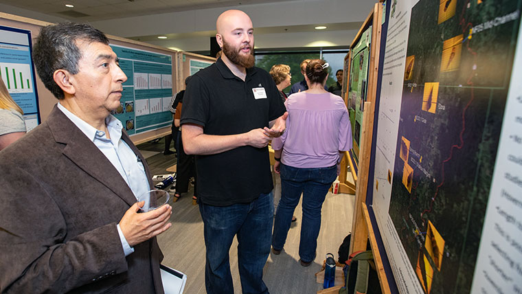A student discussing research with faculty at the CNAS Undergraduate Research Day in Plaster Student Union.