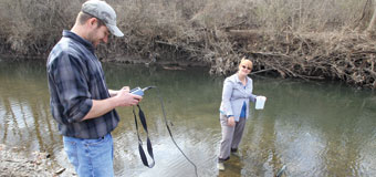 Two students test water samples at a local creek