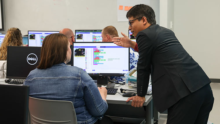 Computer science professor instructing a student during a training session.