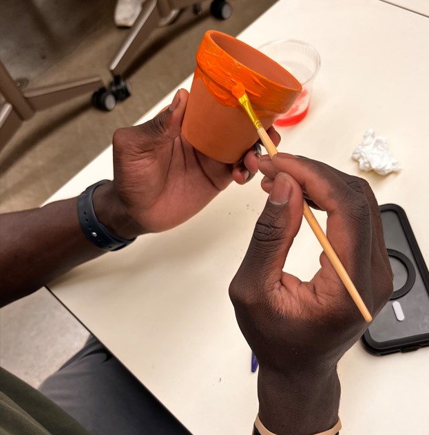 Close up of a student painting a pot