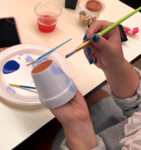 Close up of a student painting a pot